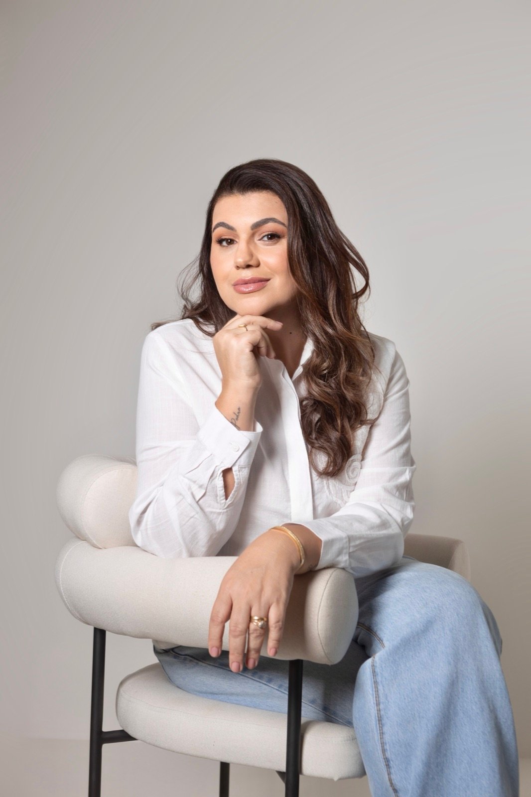Angela Westphal sentada, camisa branca, expressão serena e confiante